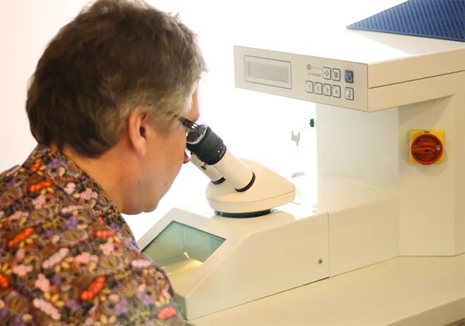 Guus kijkt door de microscoop van het laserapparaat