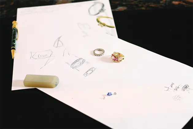 Ontwerpschetsen met ringen en losse edelstenen op de tekentafel